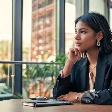 05-icf-guide-experience-coaching-career-growth A woman thinking through her next steps in an office setting while looking out the sunny windows.