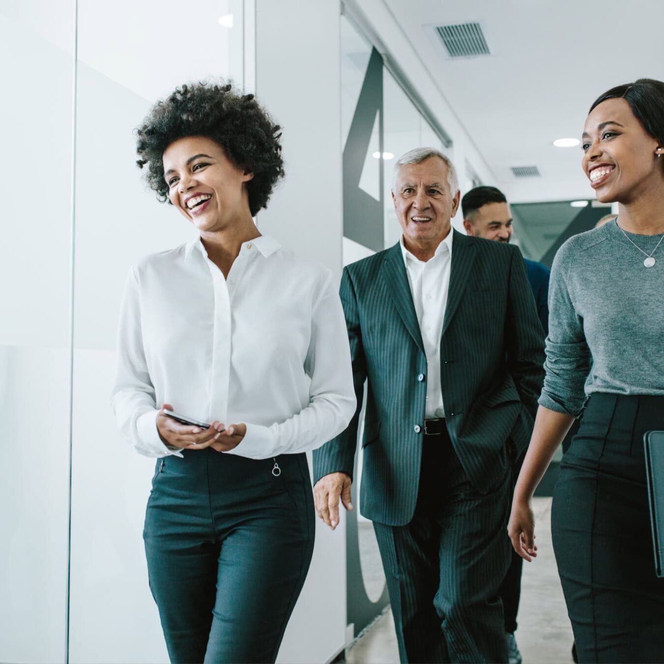 icf-about-become-a-member-coaching-culture A group of coaching professionals walk and talk through an office hallway