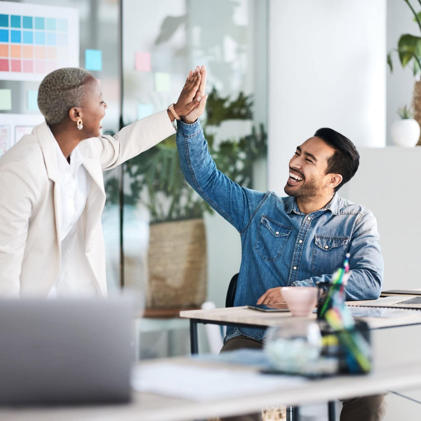 icf-about-coaching-culture-regonition A man and a woman high five in an office setting.