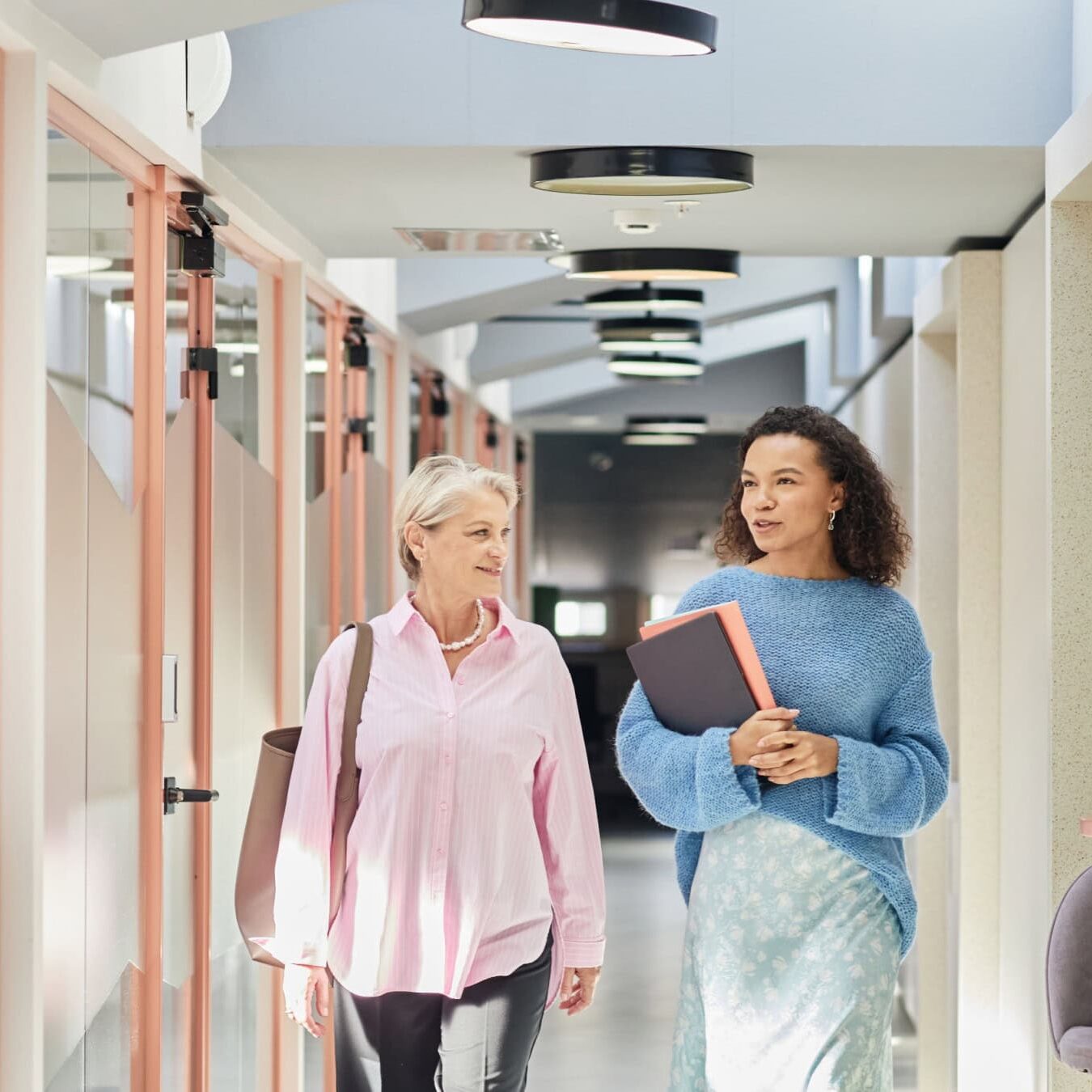 icf-about-partnership Two woman are walking through an office building talking about the ICF Business Partners