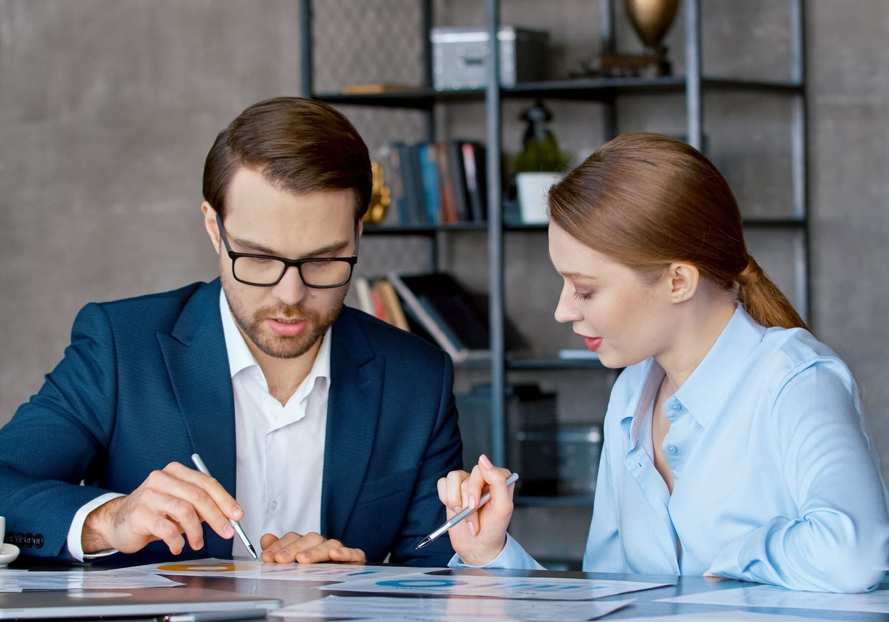 icf-about-social-impact A man and a woman go over the various coaching impact at a table in an office.