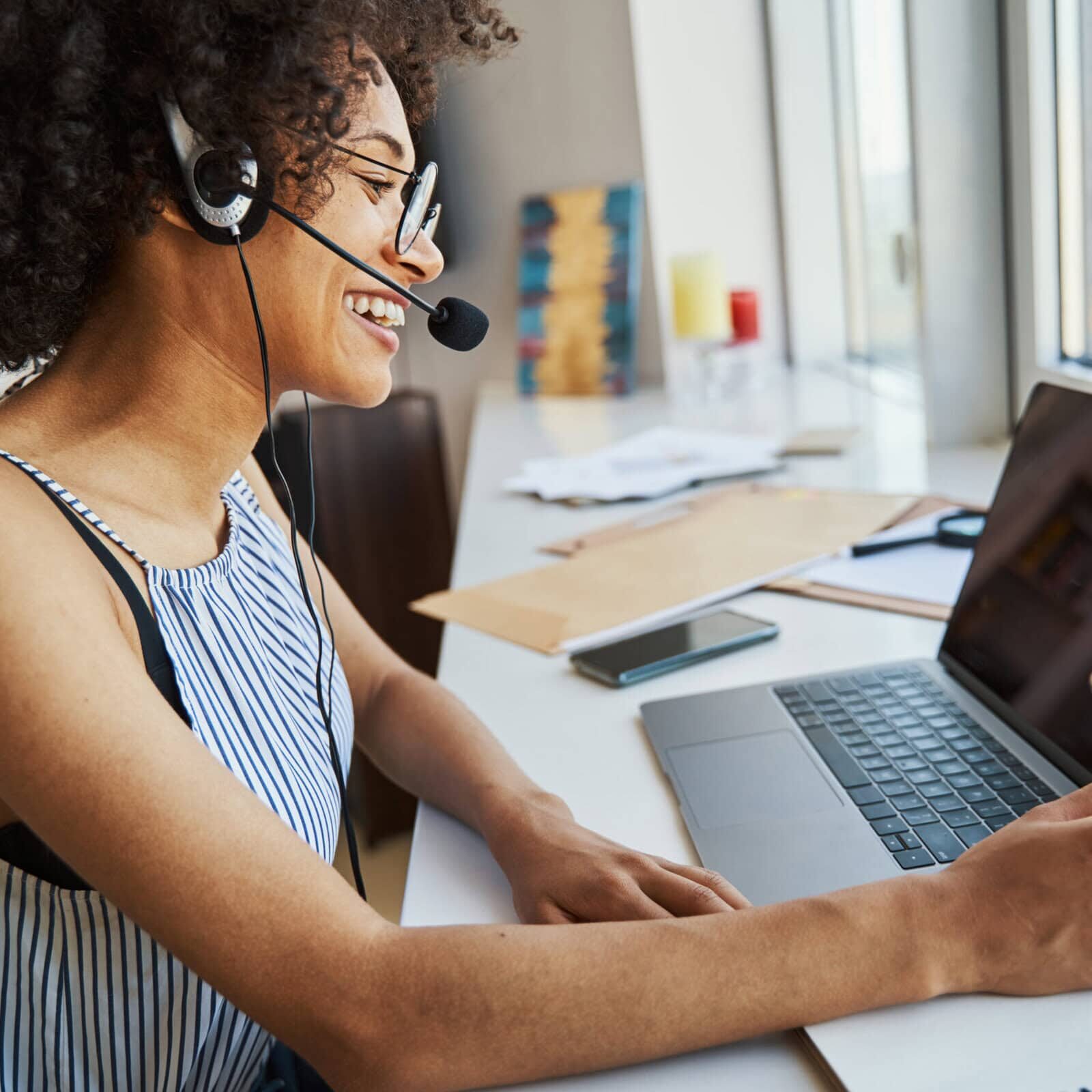 Female freelancer in eyeglasses working from home A woman shares her CCE Accredited program through the ICF Event calendar via her laptop
