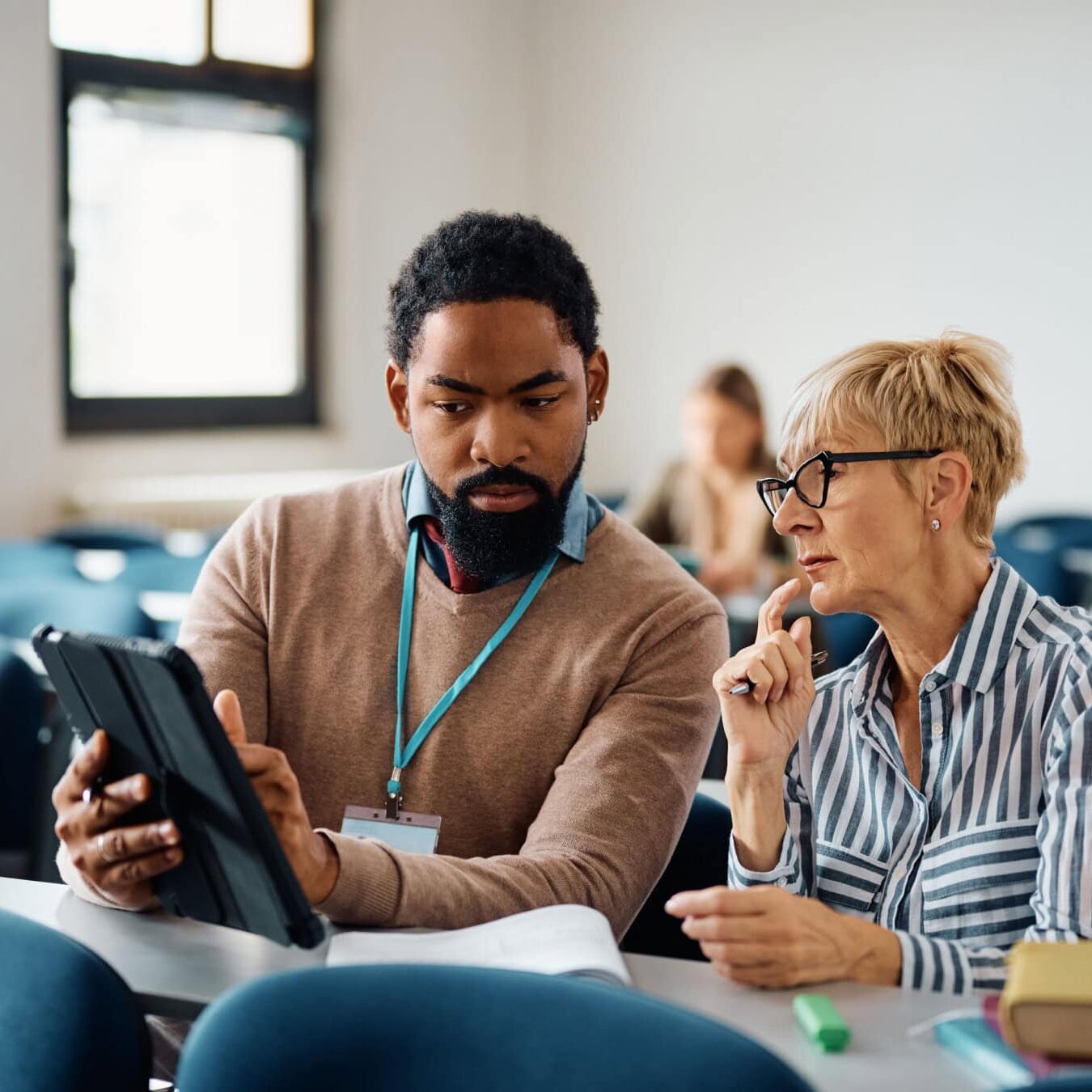 icf-coaching-culture-research-report A man and a woman look at a tablet in an educational setting.