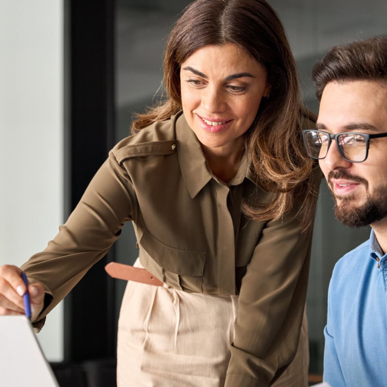 icf-credentialing-actc-exam-next-steps A woman helps a man on a laptop in an office setting
