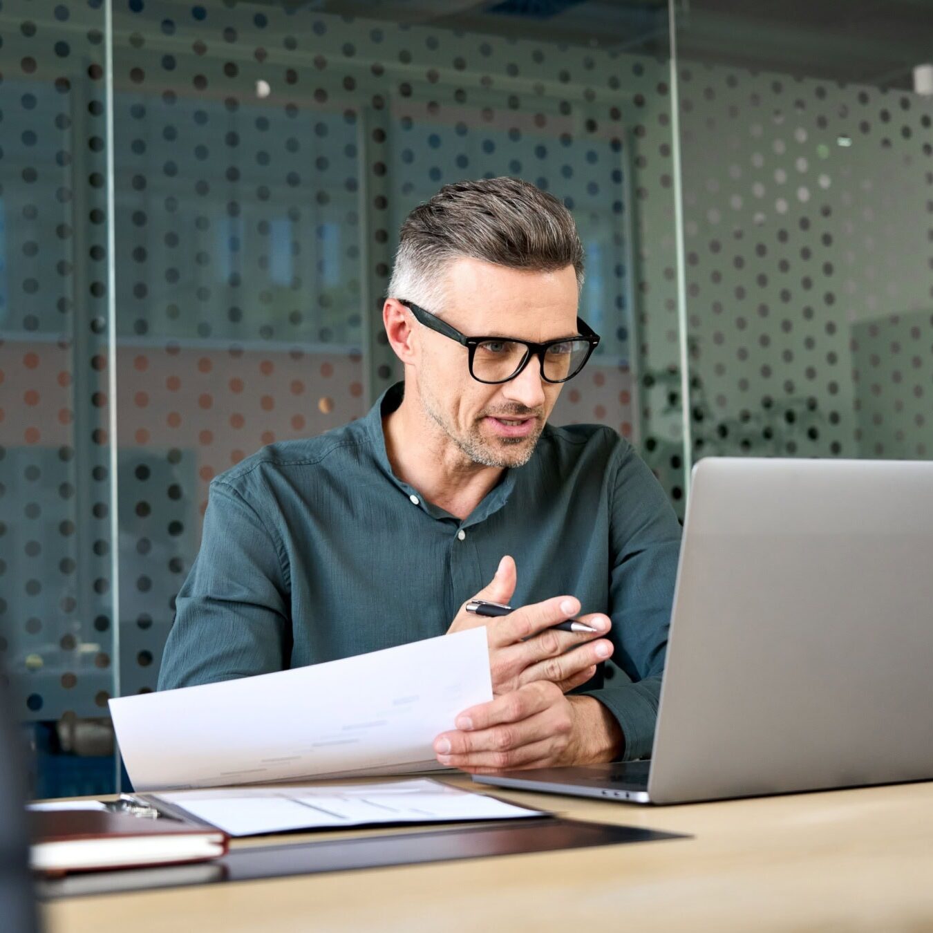 icf-credentialing-exams A man uses a laptop in an office setting to look at the ICF exams.