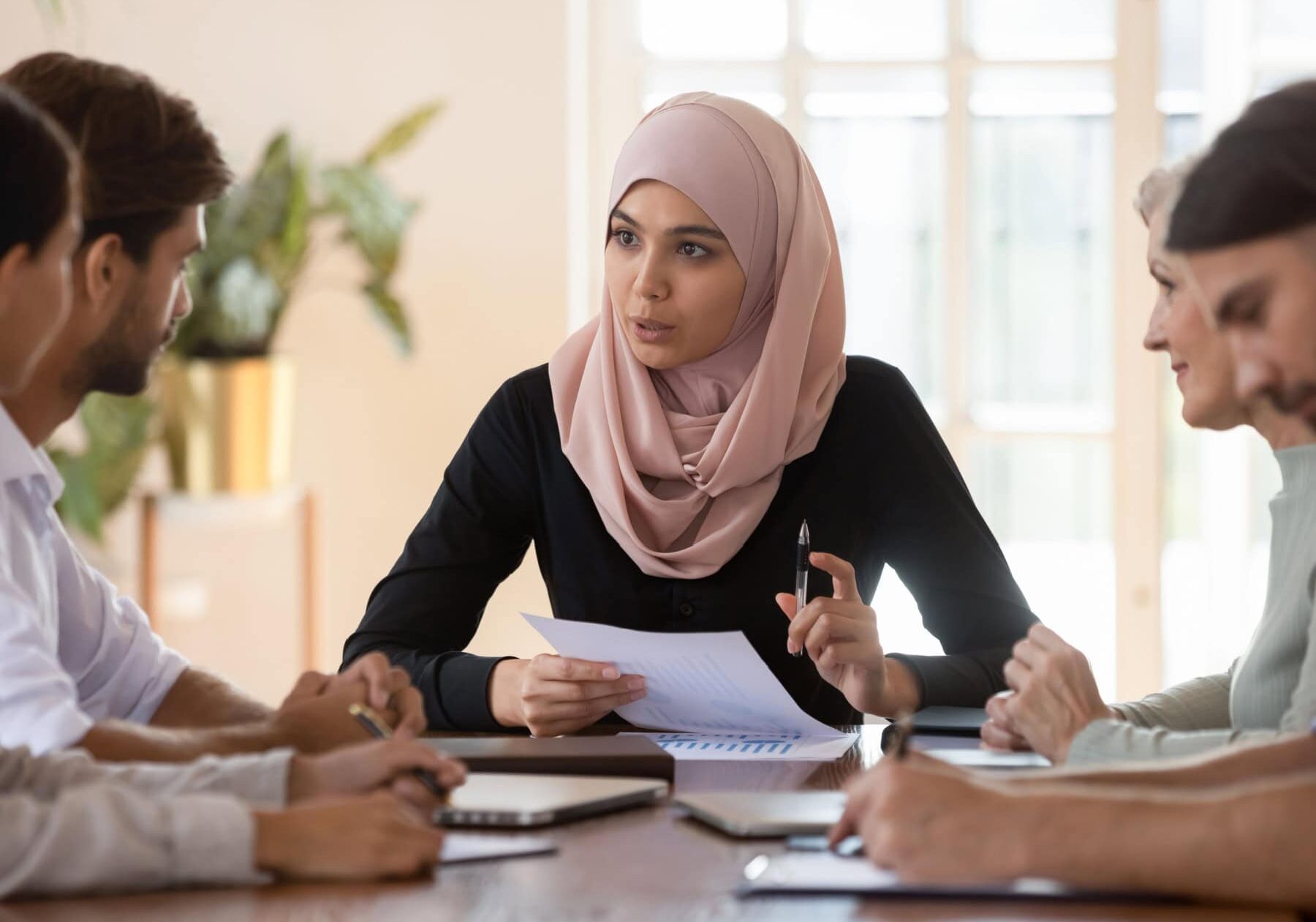 icf-credentialing-scheduling-an-icf-exam A group learns about the ICF Exam scheduling options sitting at a table.