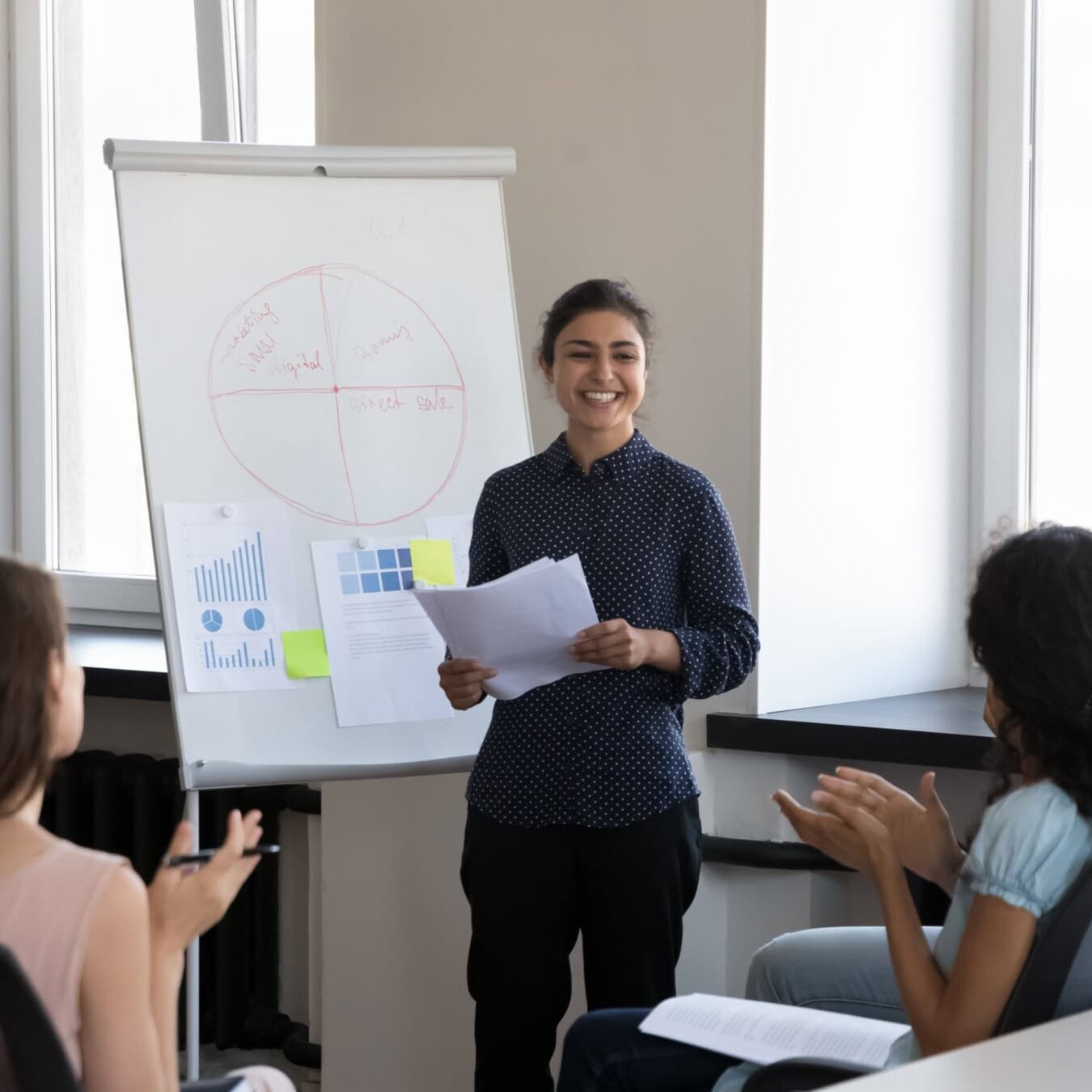 icf-credentialing-stucture-acc-exam A woman is giving a presentation to a group of people in a casual office.