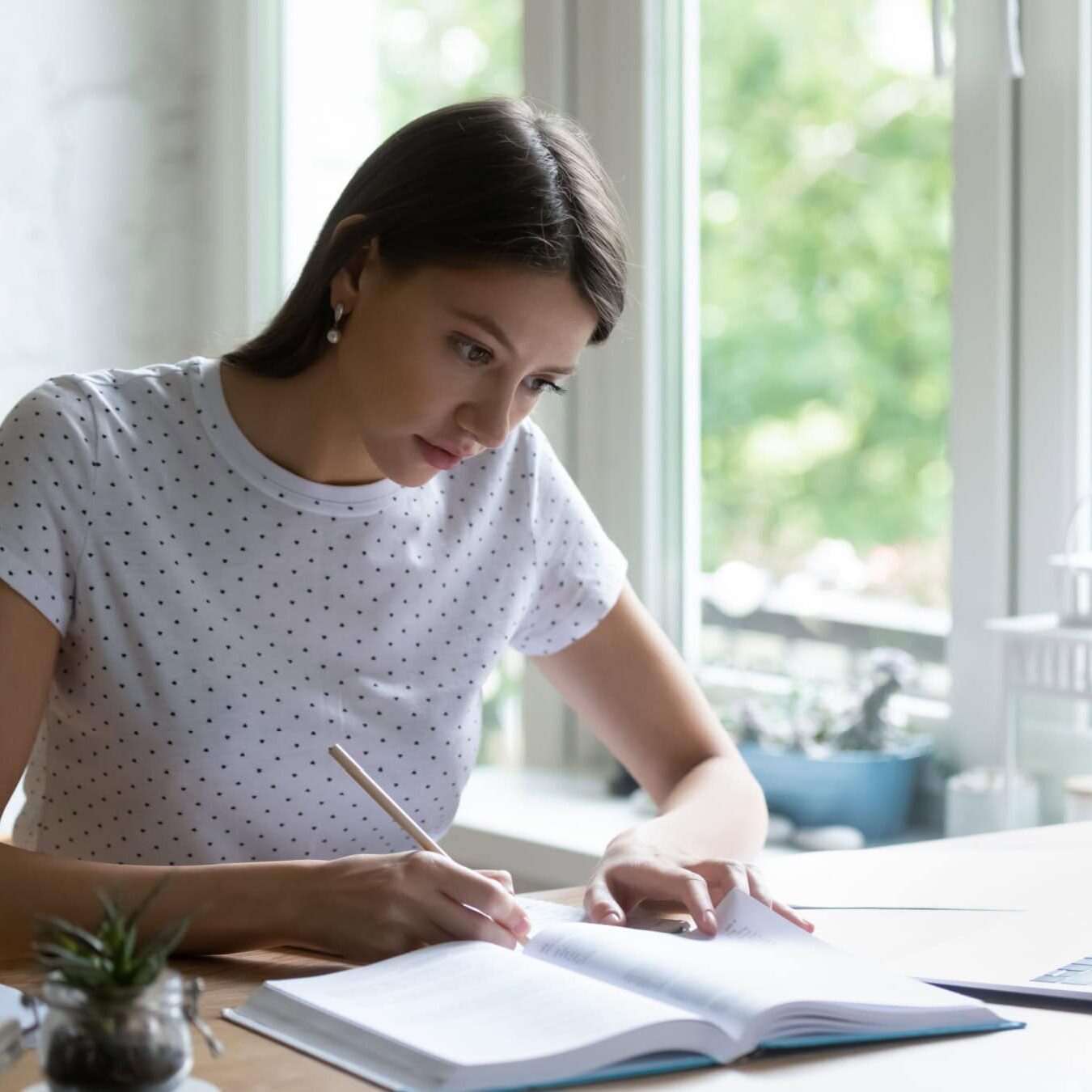 icf-credentialing-understanding-pcc-mcc-credential-exam A woman is writing in a notebook at a home office.