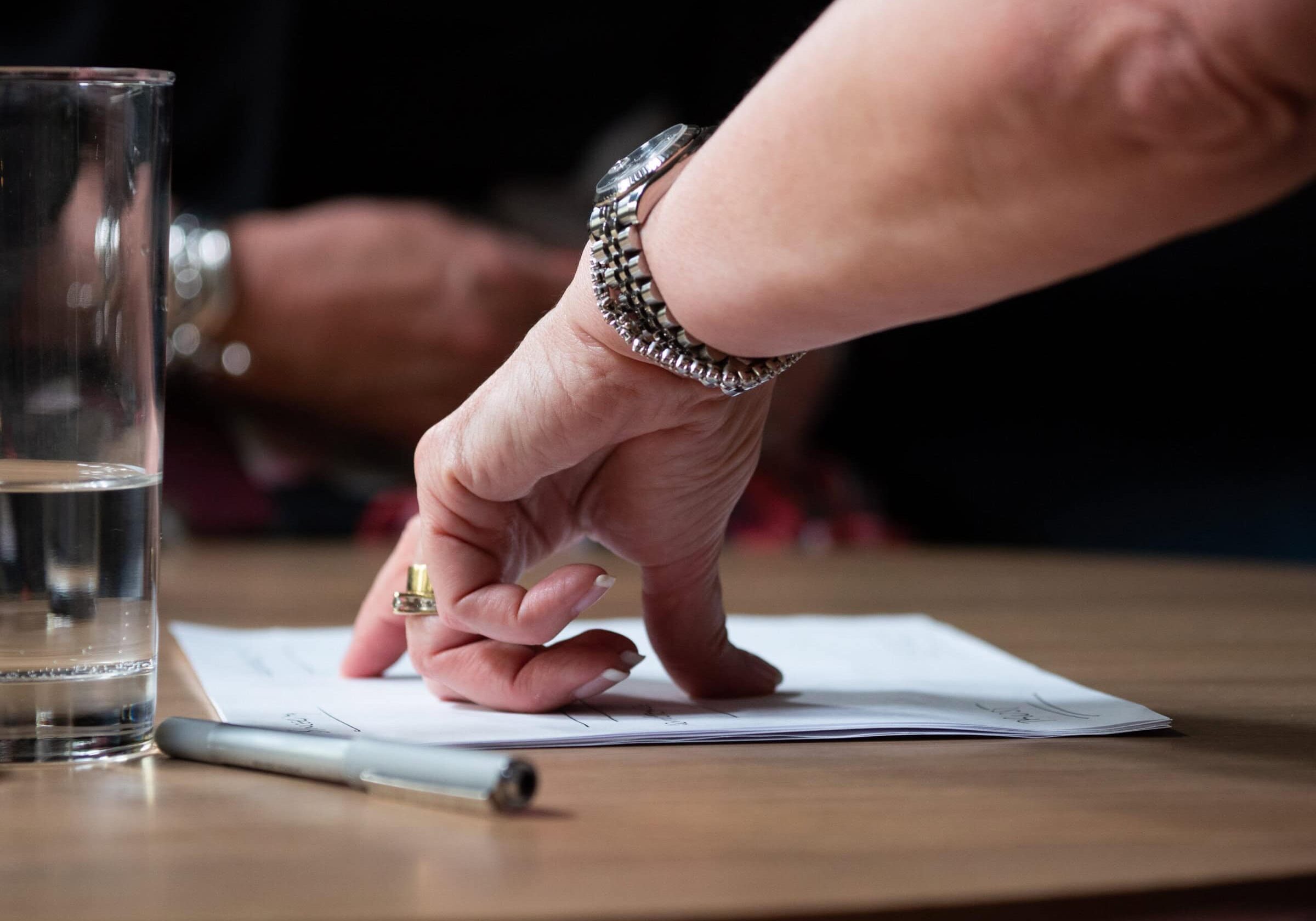 Experience Coaching: Judy's Story A hand gesturing over a document on a table, emphasizing decision-making and coaching focus.