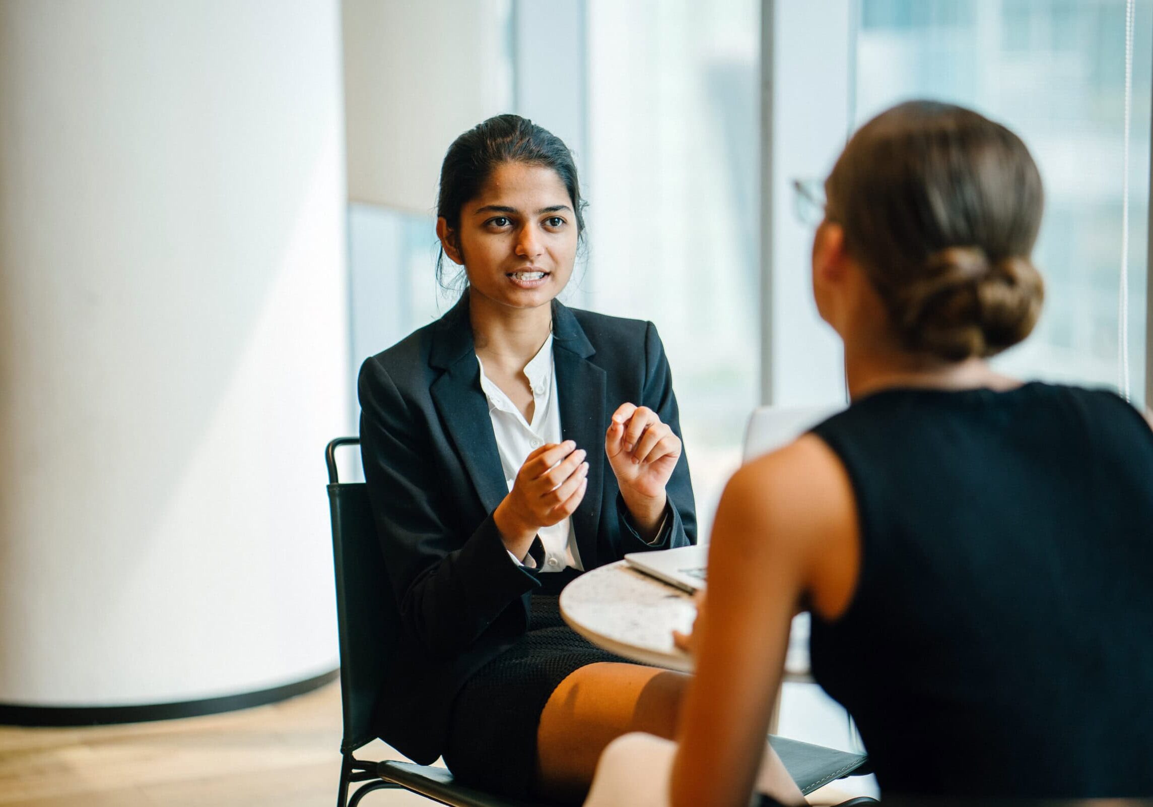 Professional Coaching Discussion Professional woman in a business suit engaged in a one-on-one coaching session with a colleague, representing ICF-certified coaching.