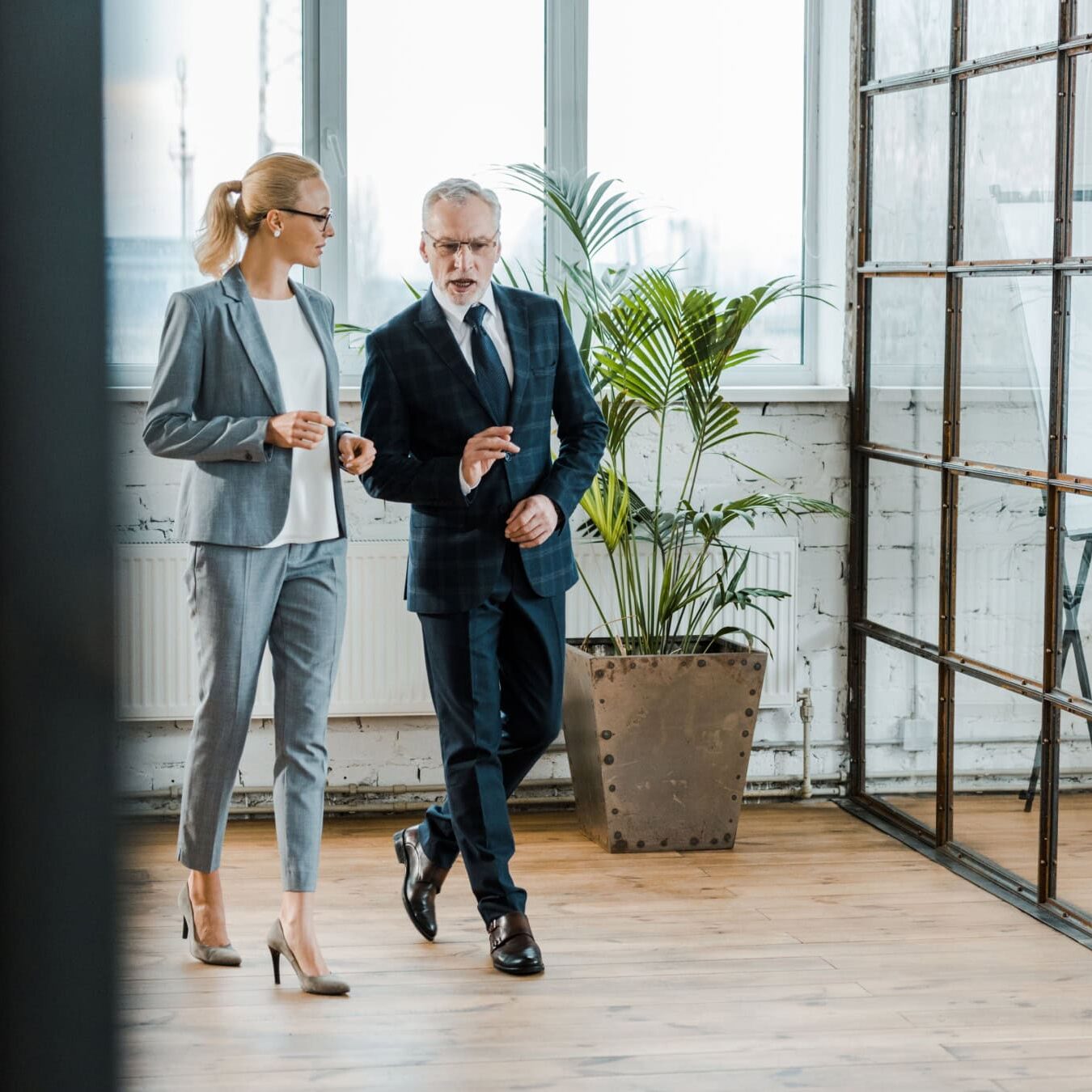 icf-resources-ai-examples A man and a woman walk through an office always talking.