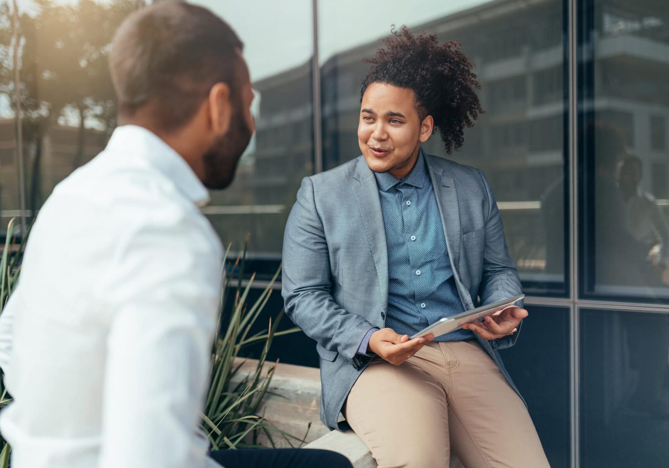 Two trendy businessmen talking and laughing casually outside whi A researcher analyzing data on coaching effectiveness displayed on a laptop screen.