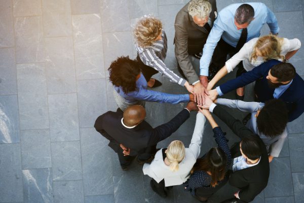 people with all hands in the middle for a group huddle