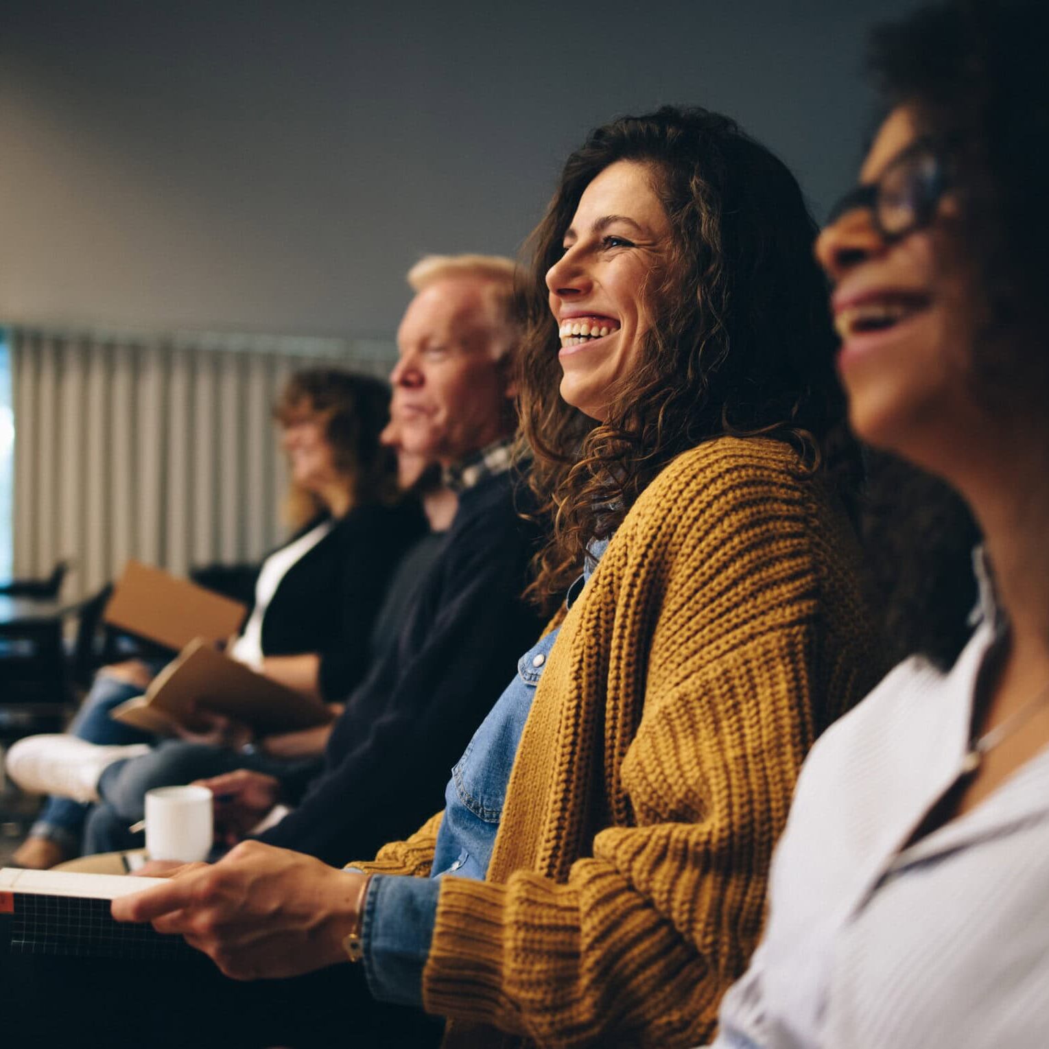Audience,Listening,To,The,Speech,Of,The,Speaker,And,Smiling. woman in focus smiling in a row at a class