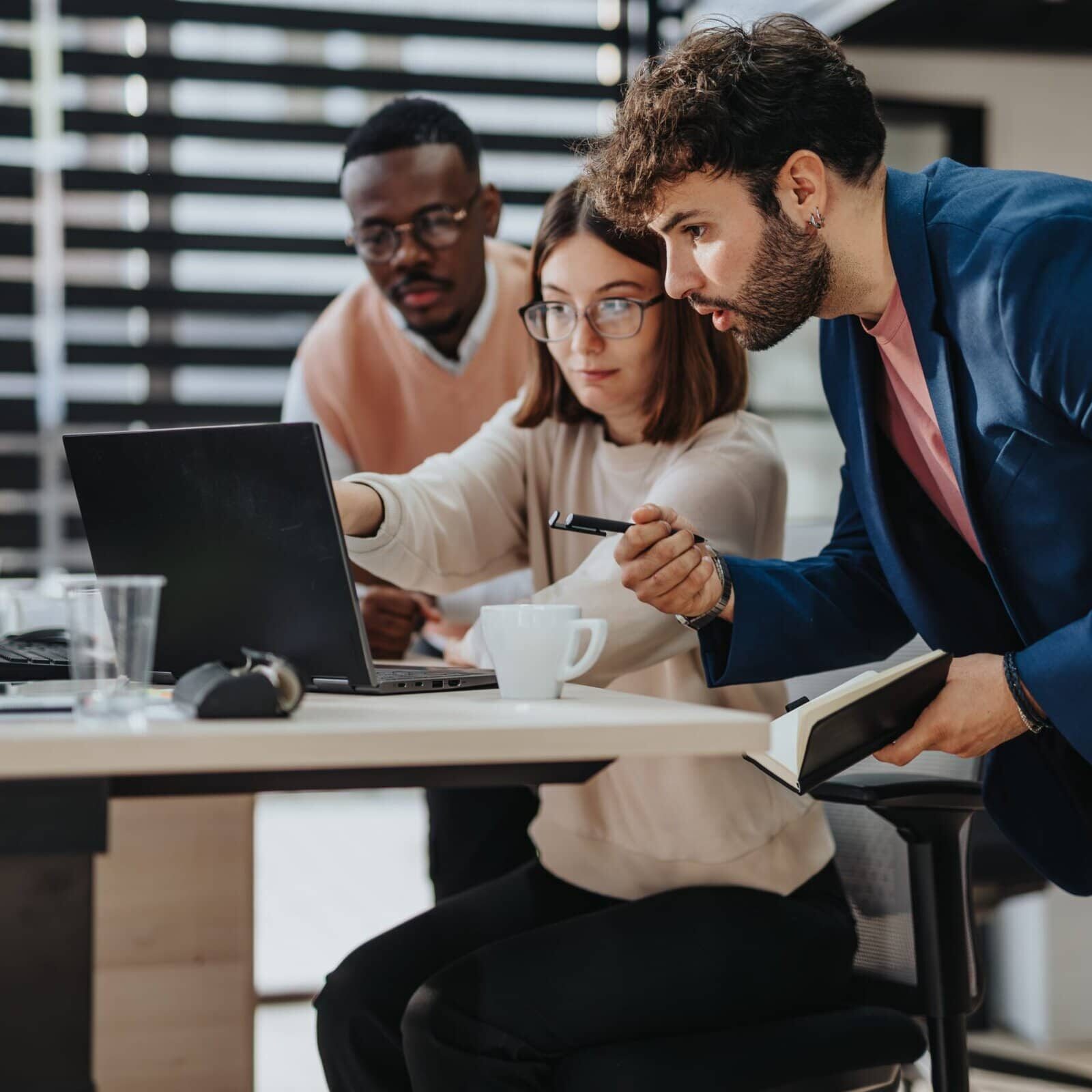 Corporate,Office,Meeting.,Multiracial,Team,Discussing,Strategic,Planning,And,Business three people at a laptop with one pointing to something on a laptop screen